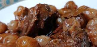 Βαθύ πιάτο με ζεστό Γίδα Στιφάδο με κομμάτια κρέατος και κρεμμυδάκια σε πηχτή κόκκινη σάλτσα