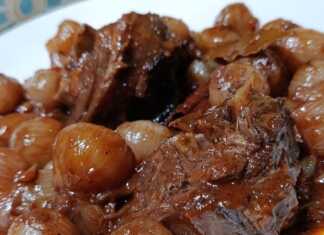 Βαθύ πιάτο με ζεστό Γίδα Στιφάδο με κομμάτια κρέατος και κρεμμυδάκια σε πηχτή κόκκινη σάλτσα