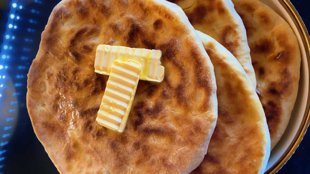 Στρογγυλό χατσαπούρι με τηγανισμένη αφράτη ζύμη και λιωμένη γέμιση τυριού, αλειμμένο με βούτυρο