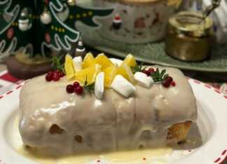 Ένα ολόκληρο μακρόστενο κέικ cranberry με λευκό γλάσο πορτοκαλιού, διακοσμημένο με φρέσκα cranberries και ξύσμα πορτοκαλιού