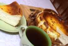 Κομμάτι από Τσιζκέικ Σαν Σεμπαστιάν με σκούρα καραμελωμένη επιφάνεια και κρεμώδες κίτρινο εσωτερικό, σερβιρισμένο με ένα φλιτζάνι καφέ