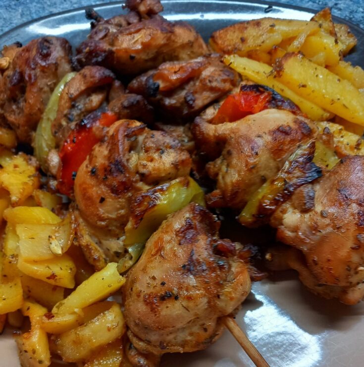 Κοντοσούβλι κοτόπουλο μπούτι με κόκκινες και πράσινες πιπεριές σε σουβλάκια, ψημένο στο φούρνο με πατάτες και χρυσαφένια κρούστα
