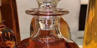 Λικέρ Κανέλας για τα Χριστούγεννα (Σπιτικό) Σπιτικό λικέρ κανέλας σε γυάλινο μπουκάλι με λίγα μπαστουνάκια κανέλας και χριστουγεννιάτικη διακόσμηση