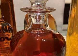 Σπιτικό λικέρ κανέλας σε γυάλινο μπουκάλι με λίγα μπαστουνάκια κανέλας και χριστουγεννιάτικη διακόσμηση