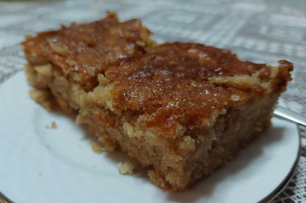 Κομμάτι μηλόπιτας που δείχνει το τριμμένο μήλο και την αφράτη υφή του κέικ.