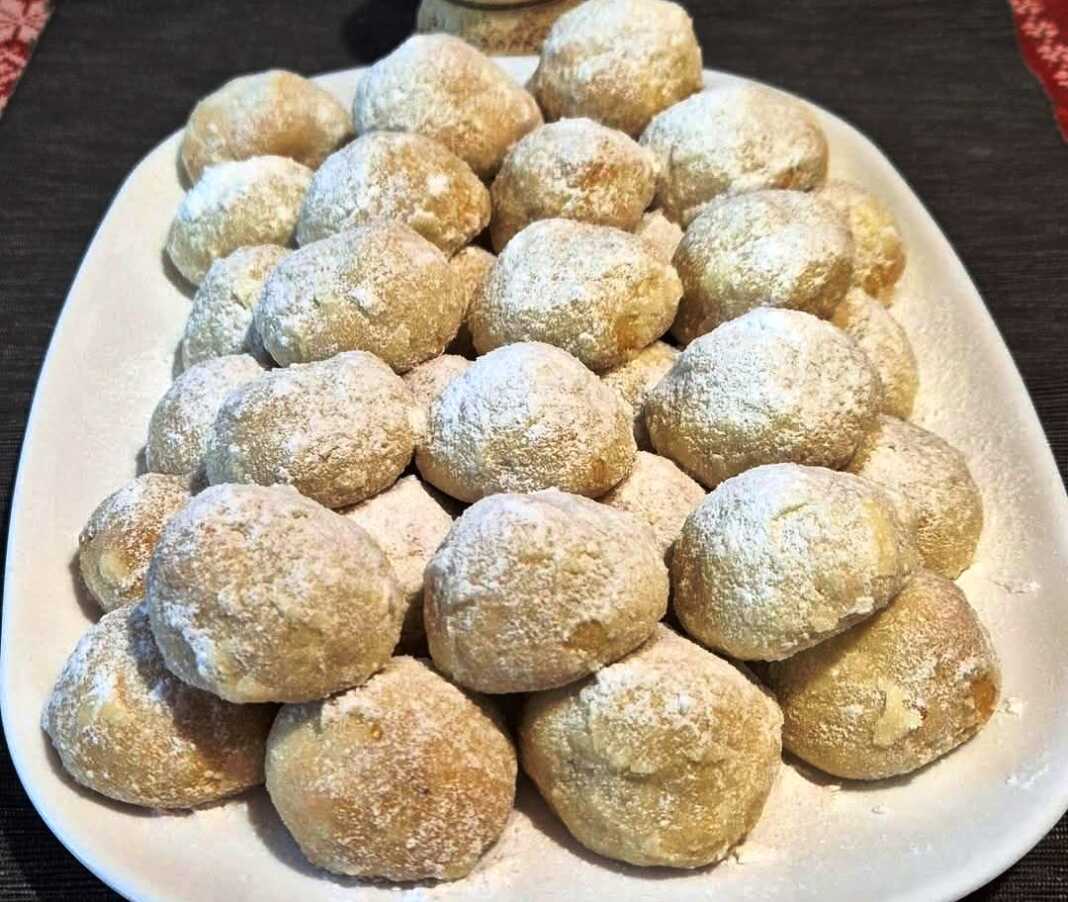 Μικρά λευκά μπισκοτάκια πασπαλισμένα με άχνη ζάχαρη, γεμιστά με ροζ λουκούμι, τοποθετημένα σε πιατέλα