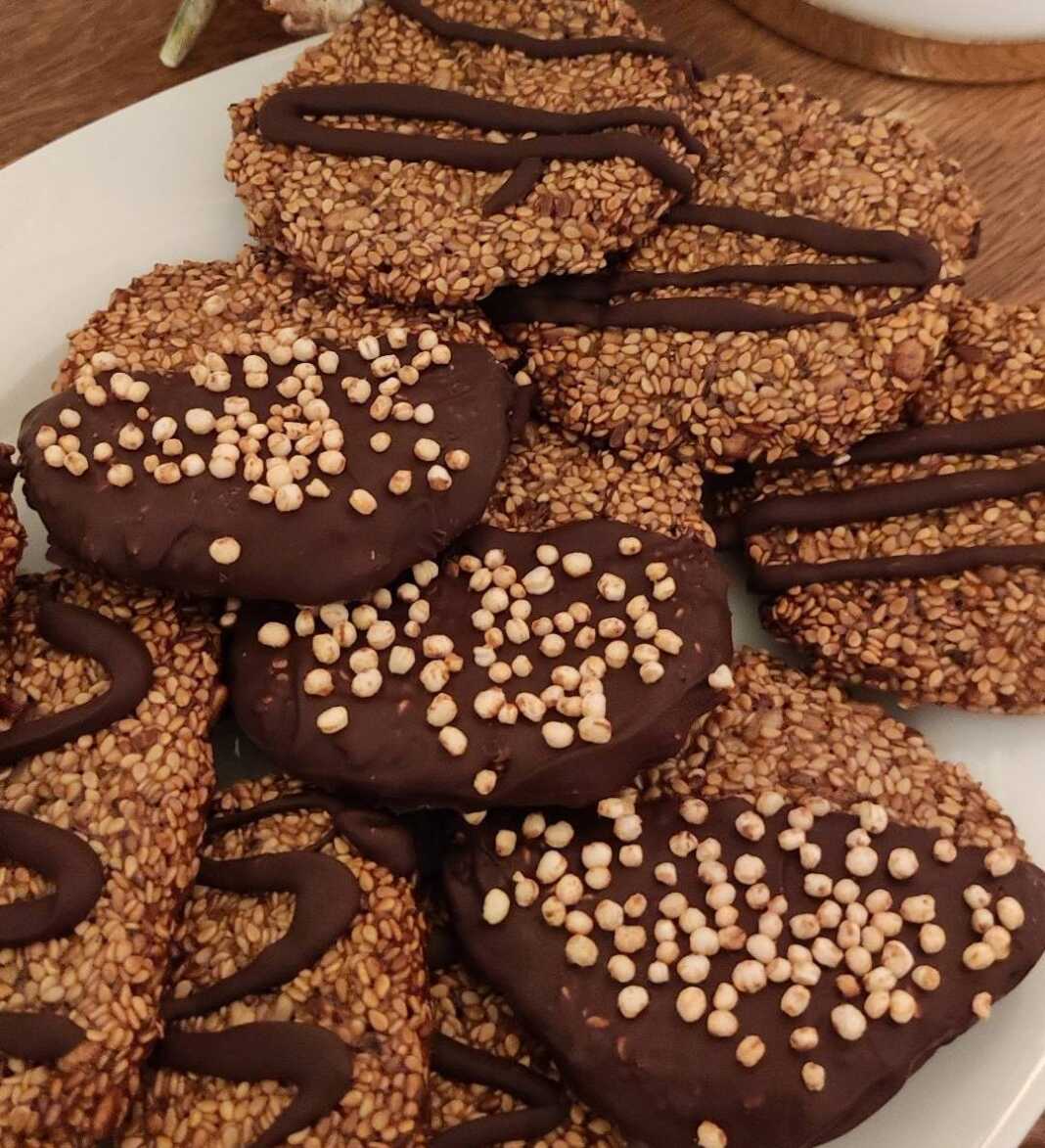 Στρογγυλά μπισκοτοπαστελάκια με σουσάμι και λιναρόσπορο, μερικά από τα οποία είναι βουτηγμένα σε πικρή σοκολάτα