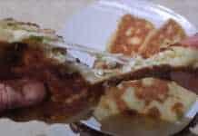 Αφράτες τηγανητές πίτες κομμένες στη μέση που αποκαλύπτουν τη γέμιση τυριού και φρέσκου κρεμμυδιού