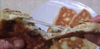 Αφράτες τηγανητές πίτες κομμένες στη μέση που αποκαλύπτουν τη γέμιση τυριού και φρέσκου κρεμμυδιού