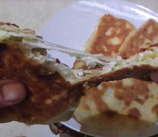 Αφράτες τηγανητές πίτες κομμένες στη μέση που αποκαλύπτουν τη γέμιση τυριού και φρέσκου κρεμμυδιού