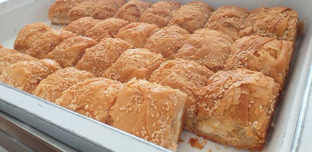 Κομμάτια από μεγάλη παραδοσιακή τυρόπιτα με χειροποίητο φύλλο και αφράτη γέμιση τυριών