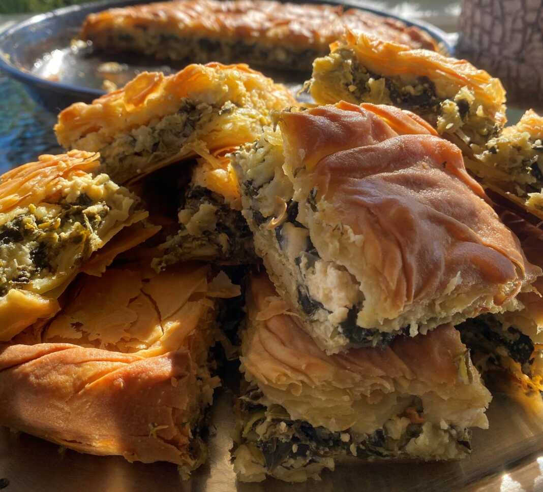 Σπιτική σπανακοτυρόπιτα με χρυσαφένια και τραγανή κρούστα, κομμένη σε κομμάτια και γεμάτη με πράσινη γέμιση