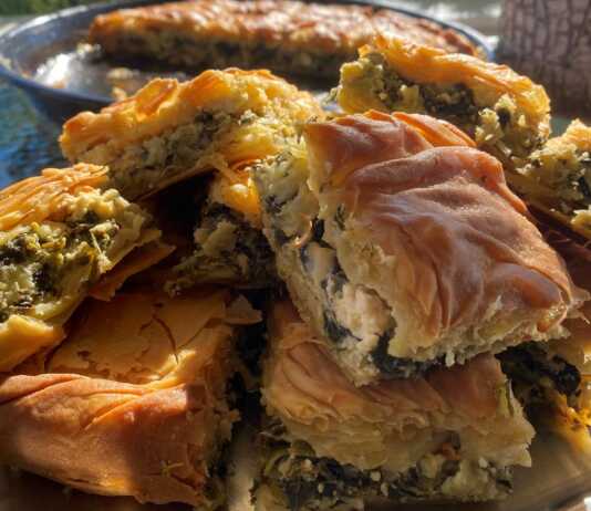 Σπιτική σπανακοτυρόπιτα με χρυσαφένια και τραγανή κρούστα, κομμένη σε κομμάτια και γεμάτη με πράσινη γέμιση