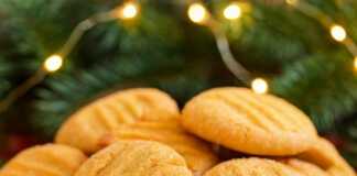 Σειρές από χρυσαφένια Χριστουγεννιάτικα μπισκότα με σχέδιο πιρουνιού στην επιφάνεια, πασπαλισμένα με κρυσταλλική ζάχαρη.