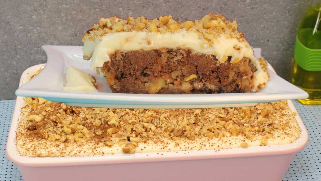 Ένα πλούσιο κομμάτι παραδοσιακής πουτίγκας με στρώσεις καρυδόπιτας, σοκολάτας και λευκής κρέμας, πασπαλισμένο με κανέλα.