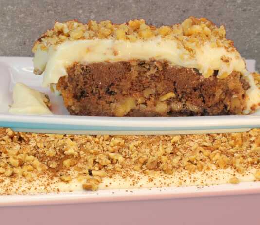 Ένα πλούσιο κομμάτι παραδοσιακής πουτίγκας με στρώσεις καρυδόπιτας, σοκολάτας και λευκής κρέμας, πασπαλισμένο με κανέλα.