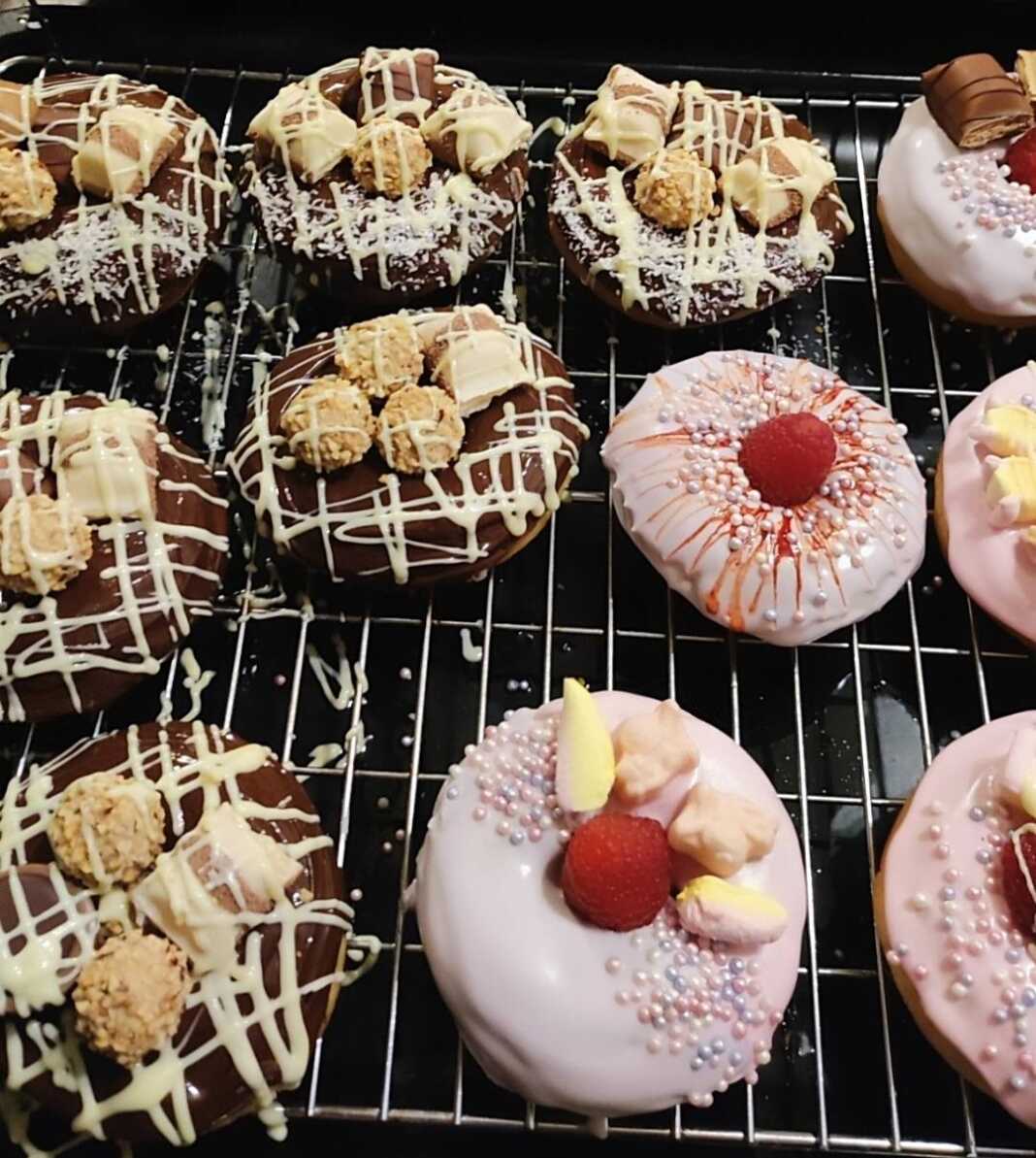 Τηγανητά ντόνατς τοποθετημένα σε πιατέλα, καλυμμένα με γλάσο σοκολάτας ή άχνη ζάχαρη, έτοιμα προς σερβίρισμα.