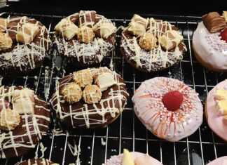 Τηγανητά ντόνατς τοποθετημένα σε πιατέλα, καλυμμένα με γλάσο σοκολάτας ή άχνη ζάχαρη, έτοιμα προς σερβίρισμα.