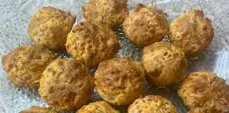 Δώδεκα αλμυρά μάφινς με κοτόπουλο, τυρί και κόκκινα κομμάτια ντομάτας, σερβιρισμένα σε καλαθάκια για μάφινς