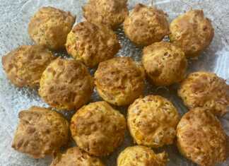 Δώδεκα αλμυρά μάφινς με κοτόπουλο, τυρί και κόκκινα κομμάτια ντομάτας, σερβιρισμένα σε καλαθάκια για μάφινς