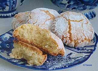 Αμυγδαλωτά Χριστουγεννιάτικα Μπισκότα: Η Καλύτερη Συνταγή για Μαλακά και Αρωματικά Γλυκά! Μια σειρά από χιονισμένα αμυγδαλωτά μπισκότα πασπαλισμένα με ζάχαρη άχνη πάνω σε γιορτινό φόντο.