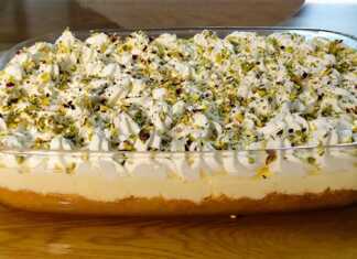 Ένα πλούσιο κομμάτι εκμέκ κανταΐφι με στρώσεις από σιροπιασμένη βάση, κρέμα και σαντιγί, πασπαλισμένο με πράσινο φιστίκι Αιγίνης.