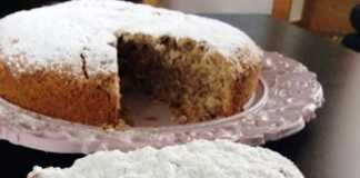 Μια αχνιστή φανουρόπιτα πασπαλισμένη με άχνη ζάχαρη, κομμένη σε τετράγωνα κομμάτια πάνω σε μια όμορφη πιατέλα.