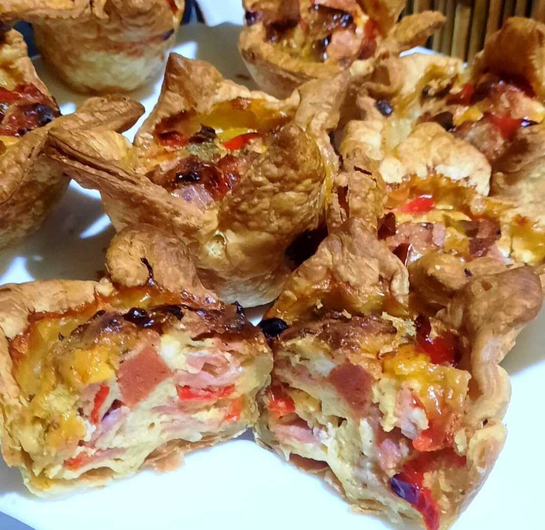 Τραγανές φωλίτσες σφολιάτας γεμισμένες με λιωμένα τυριά, ζαμπόν και χρωματιστές πιπεριές, ψημένες σε θήκες μάφιν.