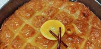 Κομμάτια από χρυσαφένιο γαλακτομπούρεκο σε πιατέλα, πασπαλισμένα με κανέλα, με την αφράτη κρέμα να φαίνεται στο εσωτερικό.