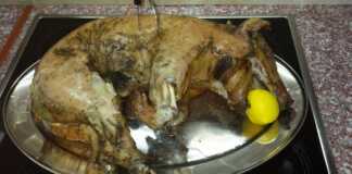 Ένα ολόκληρο ψημένο γουρουνάκι γάλακτος με χρυσαφένια τραγανή πέτσα, περιτριγυρισμένο από μελωμένες βουτυράτες πατάτες μέσα σε ένα μεγάλο ταψί.