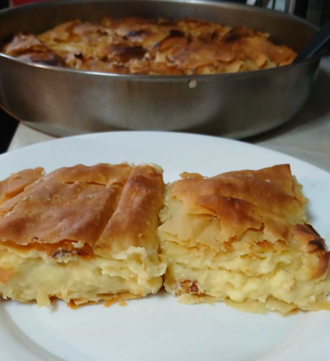 Μια λαχταριστή κασερόπιτα με χρυσάφι χωριάτικο φύλλο, κομμένη σε κομμάτια που αποκαλύπτουν την πλούσια κρέμα τυριών.