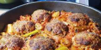 Ταψί με ροδοκοκκινισμένους κεφτέδες πάνω σε μαγειρεμένα πράσα και λάχανο με κόκκινη σάλτσα.