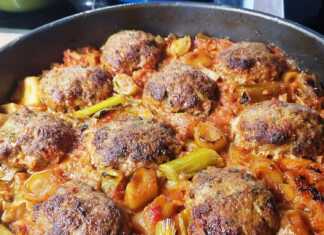 Ταψί με ροδοκοκκινισμένους κεφτέδες πάνω σε μαγειρεμένα πράσα και λάχανο με κόκκινη σάλτσα.