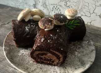 Ένας σοκολατένιος κορμός Χριστουγέννων διακοσμημένος με γλάσο σοκολάτας, μανιτάρια από μαρέγκα και άχνη ζάχαρη.