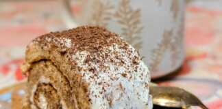 Ένα εντυπωσιακό ρολό τιραμισού πασπαλισμένο με κακάο, κομμένο σε φέτες που δείχνουν την πλούσια κρέμα και το εμποτισμένο με καφέ παντεσπάνι.