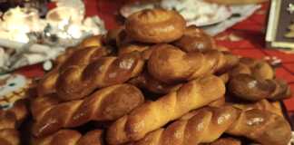 Κουλουράκια σε διάφορα σχήματα (πλεξούδες, στρόγγυλα), με χρυσαφί επιφάνεια από επάλειψη αυγού, τοποθετημένα σε ταψί.