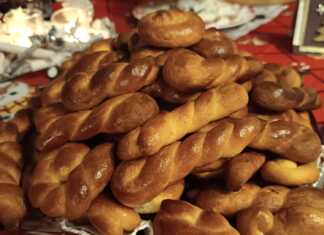 Κουλουράκια σε διάφορα σχήματα (πλεξούδες, στρόγγυλα), με χρυσαφί επιφάνεια από επάλειψη αυγού, τοποθετημένα σε ταψί.