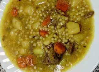 Ένα μεγάλο μπολ γεμάτο με ζεστή κρεατόσουπα μοσχαριού με κομμάτια λαχανικών και κουσκουσάκι, με λίγο πιπέρι στην επιφάνεια.