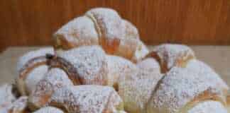 Πιάτο με μικρά χρυσαφένια κρουασανάκια με γέμιση, πασπαλισμένα με ζάχαρη άχνη.