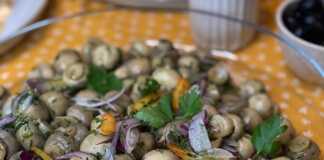 Ένα γυάλινο ταψι γεμάτο με μικρά ολόκληρα μανιτάρια (π.χ. champignon) τουρσί με ψιλοκομμένα κρεμμύδια και λάδι.