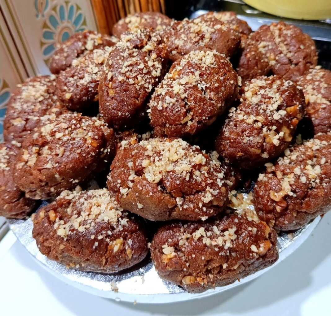 Μελομακάρονα μελωμένα και πασπαλισμένα με μπόλικο τριμμένο καρύδι, τοποθετημένα σε μια γιορτινή πιατέλα.