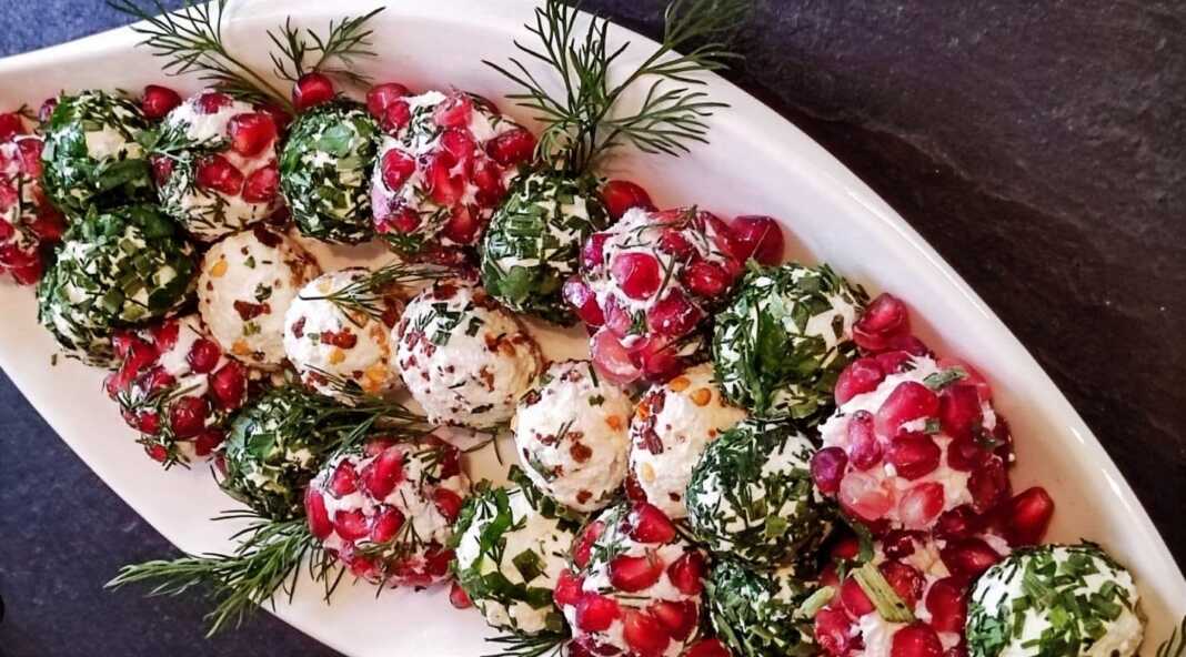 Πολύχρωμες μπαλίτσες τυριού με ρόδι και ξηρούς καρπούς δίπλα σε τυρένια δεντράκια στολισμένα με πάπρικα.