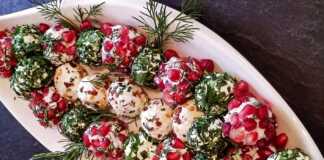 Πολύχρωμες μπαλίτσες τυριού με ρόδι και ξηρούς καρπούς δίπλα σε τυρένια δεντράκια στολισμένα με πάπρικα.