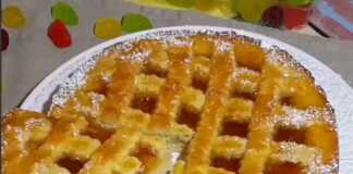 Μια χρυσαφένια πάστα φλώρα με πλέγμα ζύμης και πλούσια μαρμελάδα βερίκοκο σε ένα ταψί.