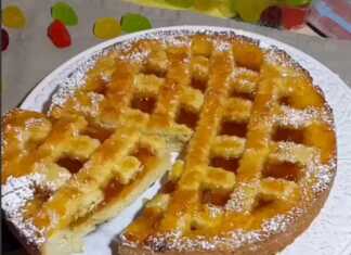 Μια χρυσαφένια πάστα φλώρα με πλέγμα ζύμης και πλούσια μαρμελάδα βερίκοκο σε ένα ταψί.