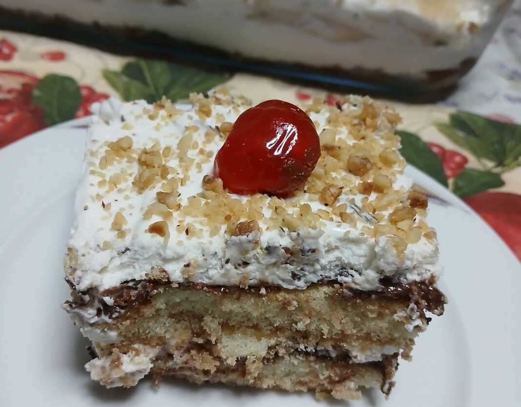 Γλυκό ταψιού πολυεπίπεδο με σοκολάτα, σαντιγί και καβουρδισμένα φουντούκια στην επιφάνεια.