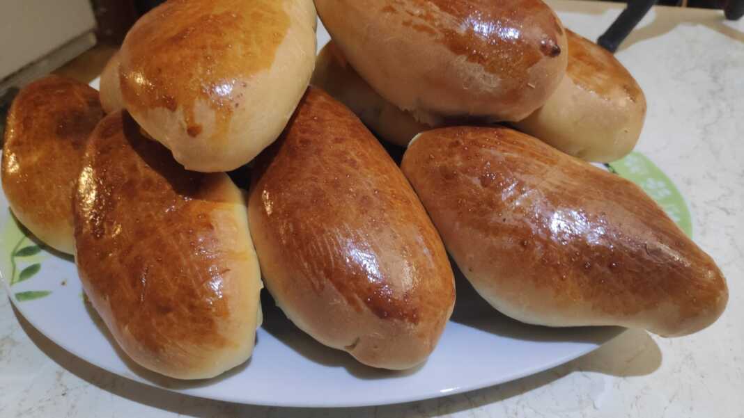 Χρυσαφένια και αφράτα πιροσκί τοποθετημένα σε ταψί με αντικολλητικό χαρτί μόλις βγαλμένα από τον φούρνο