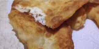 χρυσαφένιες τηγανητές πίτες με τυρί σε πιατέλα, με μία κομμένη που δείχνει τη λιωμένη γέμιση φέτας.