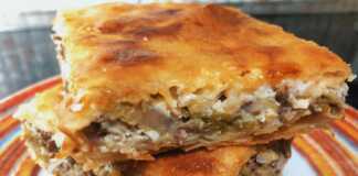 Μια λαχταριστή πρασόπιτα με κιμά σε ορθογώνιο ταψί, κομμένη σε τετράγωνα κομμάτια και ροδοκοκκινισμένη.