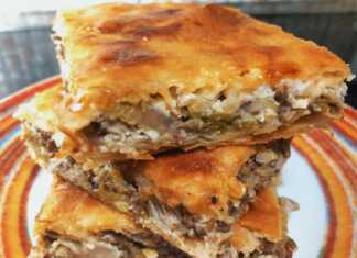 Μια λαχταριστή πρασόπιτα με κιμά σε ορθογώνιο ταψί, κομμένη σε τετράγωνα κομμάτια και ροδοκοκκινισμένη.